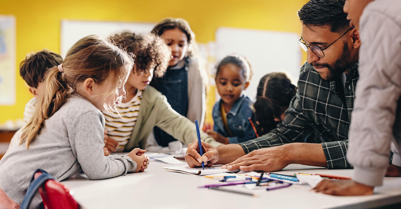 Ein Lehrer hilft einer Gruppe konzentrierter Kinder beim Lernen in einem lebendigen Klassenzimmer.